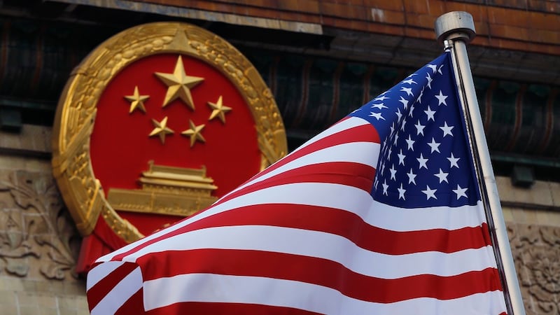 An American flag is flown next to the Chinese national emblem during a welcome ceremony for...