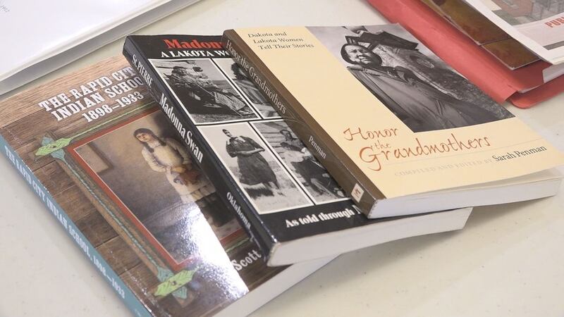 A volunteer of the Rapid City Indian Boarding School Research team brings books to the meeting...